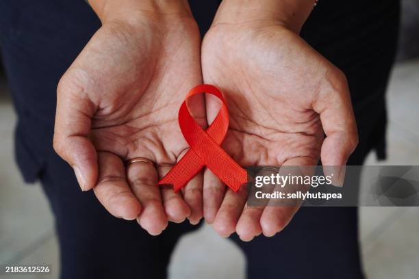woman holding red aids awareness ribbon - hiv awareness stock pictures, royalty-free photos & images