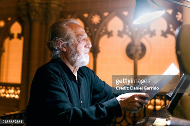 organist preparing the sheet music and placing it on the stand before starting the concert. - musical theater stock pictures, royalty-free photos & images