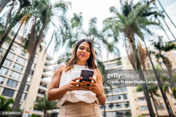 mujer de negocios mediana adulta que usa el teléfono móvil al aire libre - cali fotografías e imágenes de stock