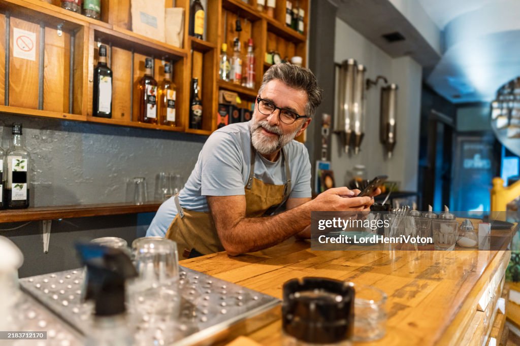 Male barista using smartphone at work