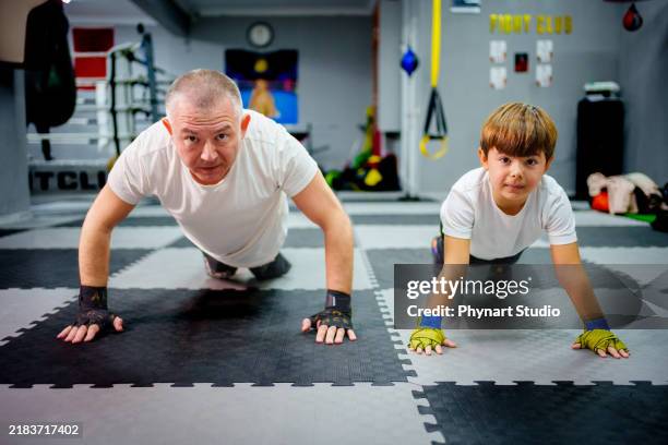 father and son pose for the camera while doing push-ups together during boxing training - boy sweating stock pictures, royalty-free photos & images