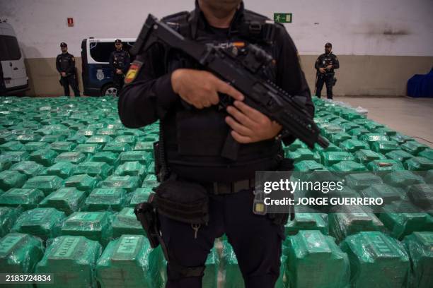 Spanish National Police and Customs officers stand next to packages of cocaine that were found in a container from Ecuador, during a police press...