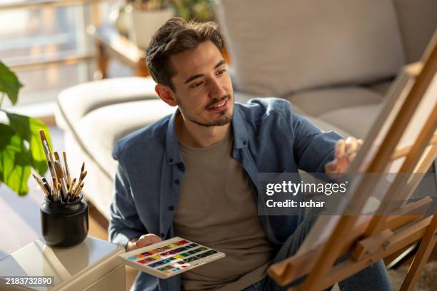 a painter paints artistic pictures on canvas in his spare time at home - easel stock pictures, royalty-free photos & images
