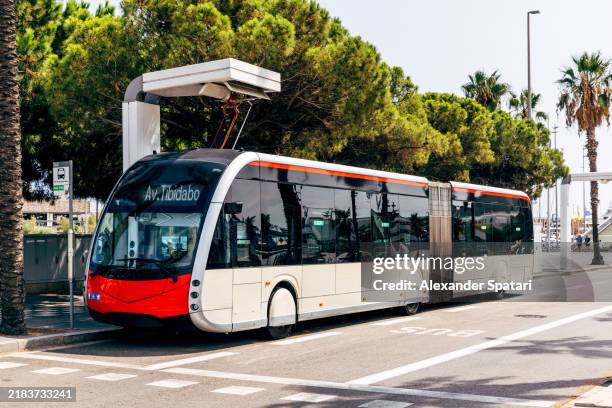 stationary electric bus charging at the charging station, barcelona, spain - öffentliches verkehrsmittel stock-fotos und bilder