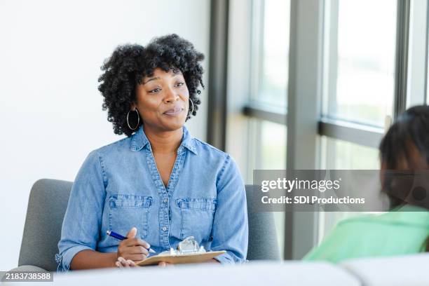 counselor takes notes during counseling session - maatschappelijk werker stockfoto's en -beelden