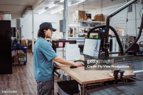 male employee operating large format printer and paper cutter in factory - tryckeri bildbanksfoton och bilder