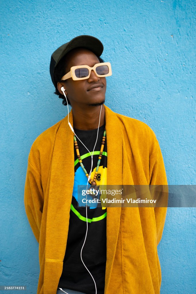Joven africano seguro de sí mismo escuchando música desde su teléfono