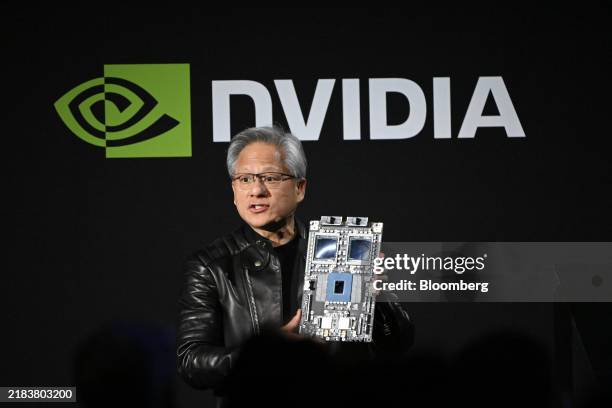 Jensen Huang, co-founder and chief executive officer of Nvidia Corp., holds up the company's AI accelerator chips for data centers as he speaks...