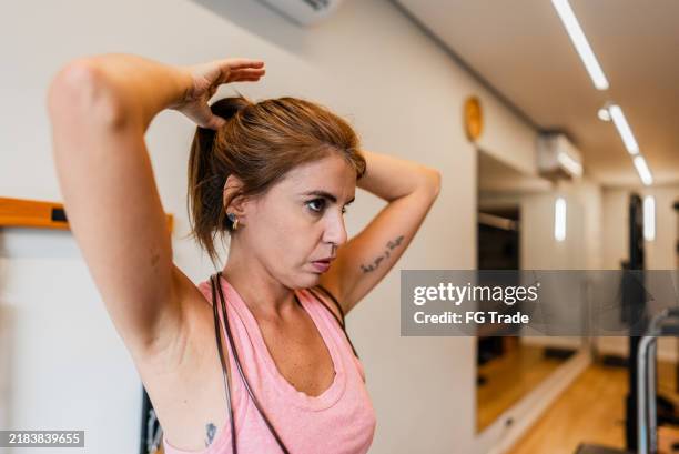 mid adult woman tying her hair at a pilates studio - hair back stock pictures, royalty-free photos & images