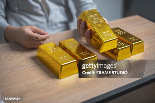 Person at a table with five gold bars, possibly assessing their weight or authenticity. Wealth, investment, or financial security concept. Person at a table with five gold bars, possibly assessing their weight or authenticity. Wealth, investment, or financial security concept.