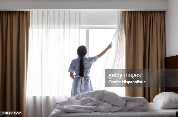 maid cleaning a hotel room and opening the drapes - serviço de quarto imagens e fotografias de stock