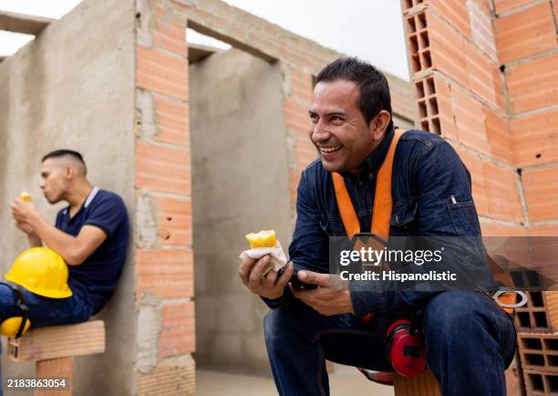 happy construction worker eating empanada while taking a break from work - construction workers laughing stock pictures, royalty-free photos & images