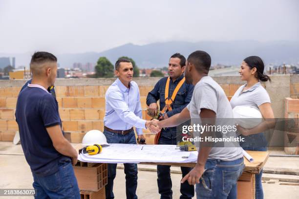 architect greeting a construction worker with a handshake at a construction site - construction site visit stock pictures, royalty-free photos & images