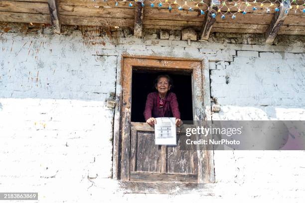 Woman watches through a traditional window in the village of Makwanpur, Nepal, on November 12, 2024.