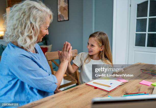grandma and granddaughter giving a high-five to each other after finishing homework - coloured pencil ends stock pictures, royalty-free photos & images