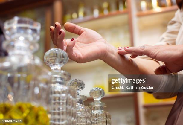 woman testing perfume on her wrist, close-up of hands - perfume stock pictures, royalty-free photos & images