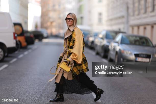 Karin Teigl is seen wearing aviator glasses with a rounded black frame from Andy Wolf; an oversized jacket in beige, yellow, red, and black made of...