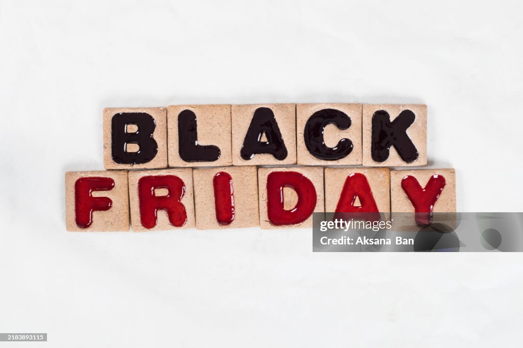 Sale day. Black friday. Square cookies in black and red marmalade filling in the shape of the words Black Friday. White background.