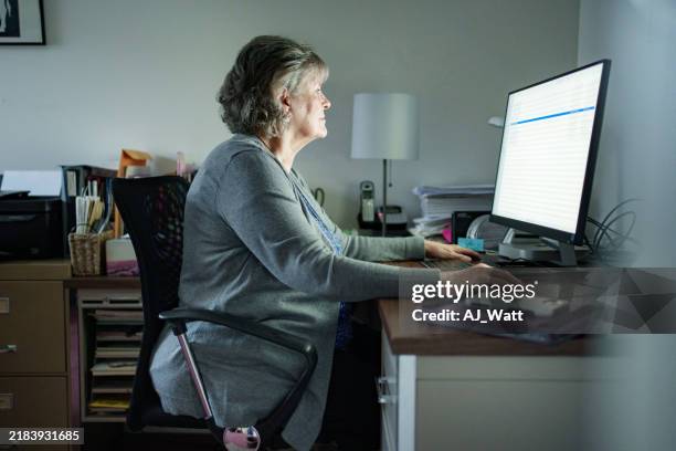 senior woman working at a computer in home office setting - staring at screen stock pictures, royalty-free photos & images