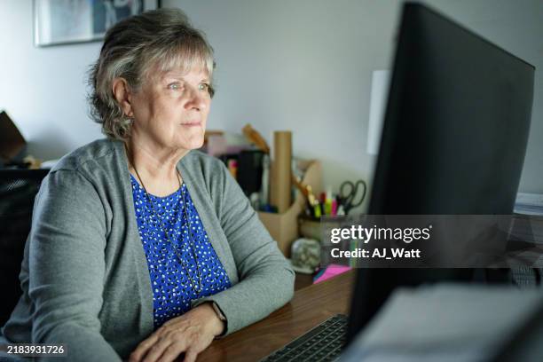 senior woman working at a computer in home office setting - staring at screen stock pictures, royalty-free photos & images