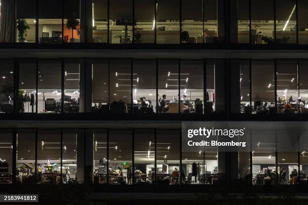 Employees at their desks seen through the windows of the Alibaba Group Holding Ltd. Headquarters in Hangzhou, China, on Monday, June 19, 2023....