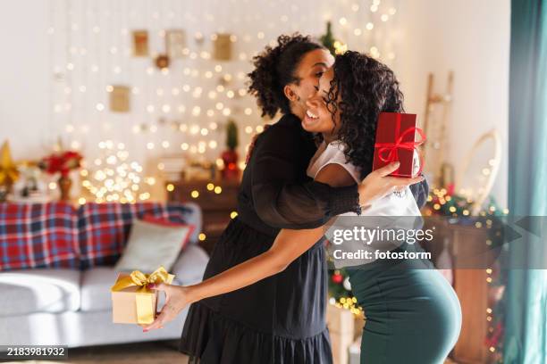 girlfriends hugging after exchanging christmas presents - festieve stemming stockfoto's en -beelden