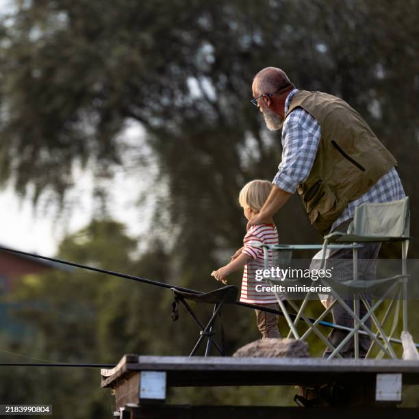 grandfather and grandson fishing together at a tranquil lake - legacy concept stock pictures, royalty-free photos & images
