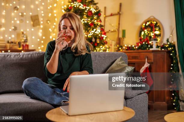 cheerful woman having wine and using laptop during christmas - chardonnay grape stock pictures, royalty-free photos & images