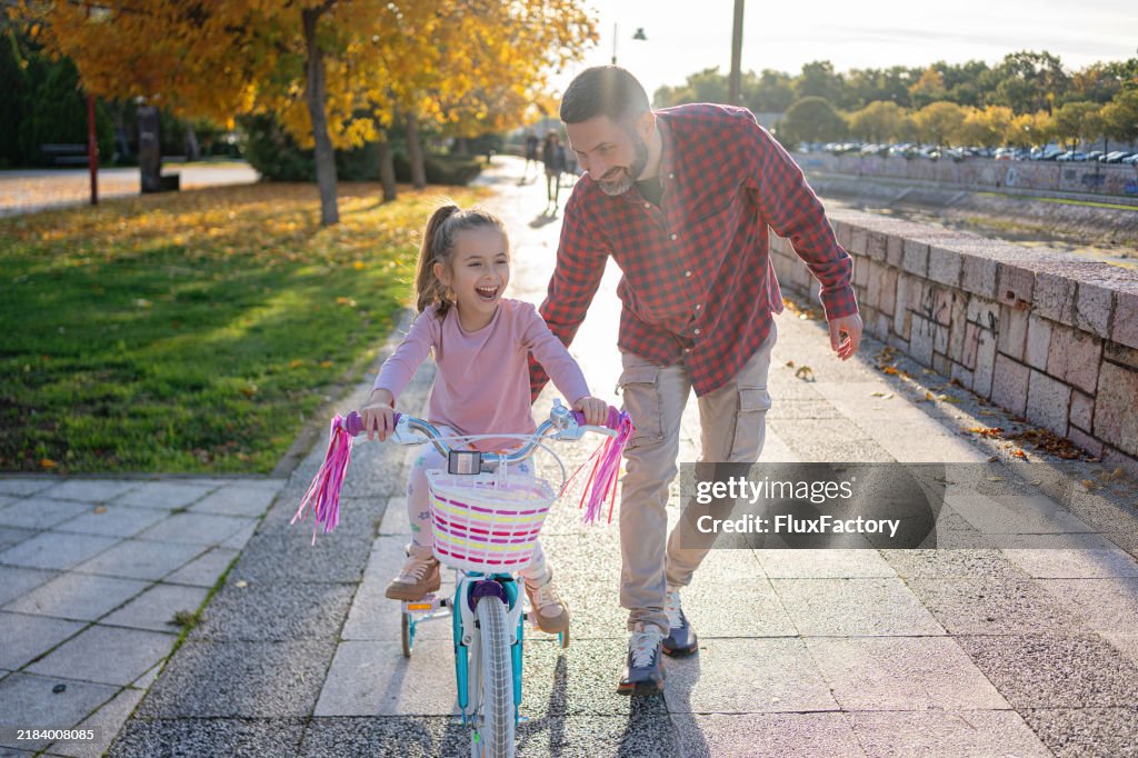 Dad and daughter bonding while he learning her to ride a bike