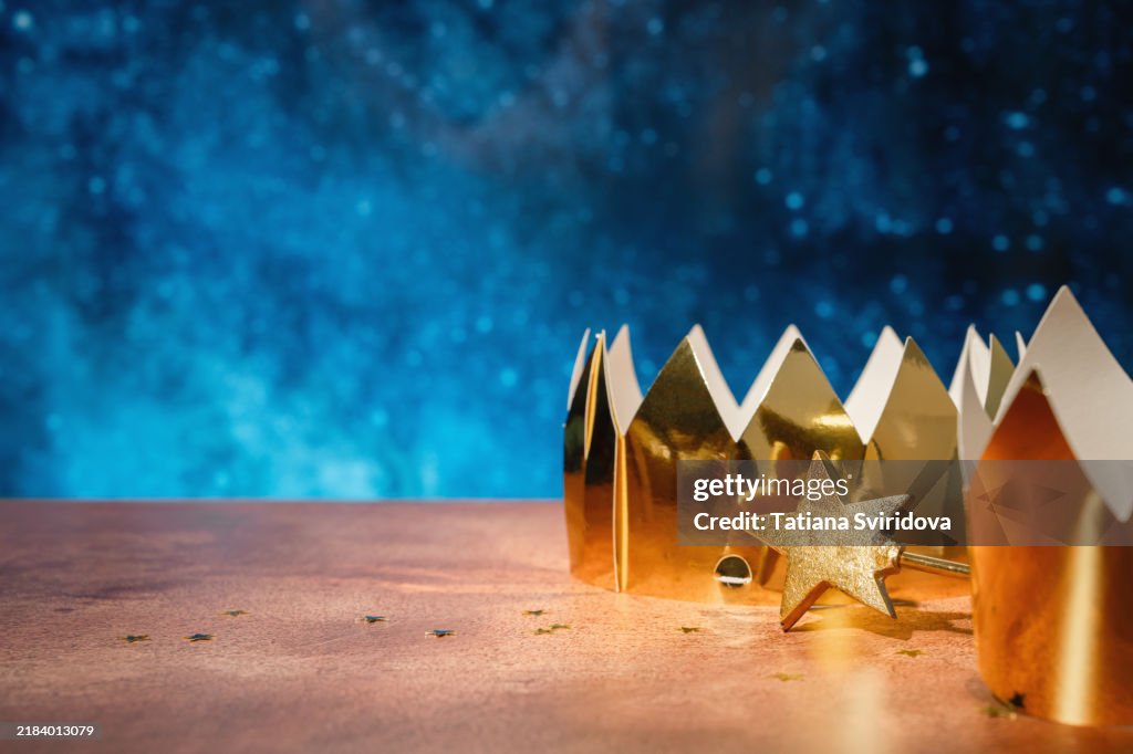 Crowns and star wand on table with dark blue background