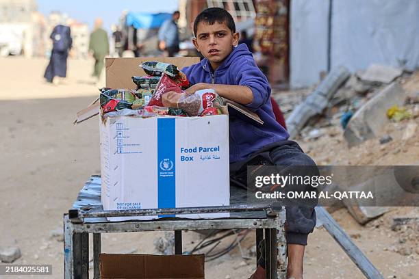 Palestinian boy sits by a UN World Food Program box of food items, in Gaza City on November 14 amid the ongoing war between Israel and the...