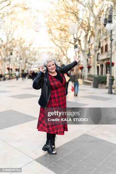 stylish mature woman enjoying music and freedom in city center - voluptuous mature women foto e immagini stock