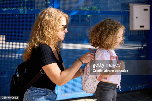 mother helping daughter putting backpack before school - school gates stock pictures, royalty-free photos & images