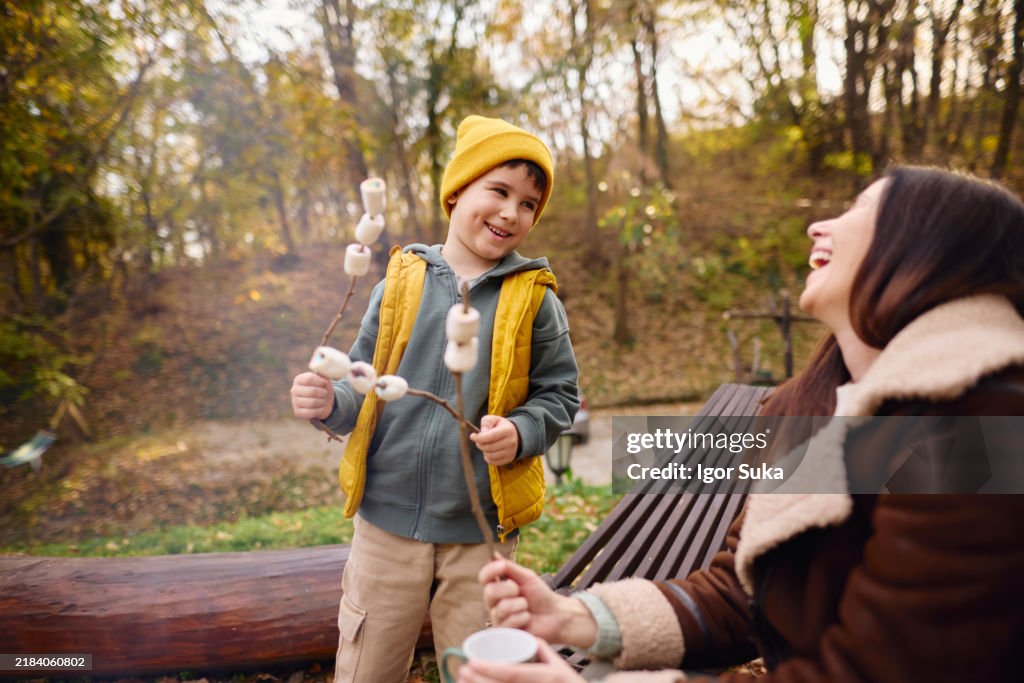 Mother and Son Enjoying Marshmallow Roast in Autumn Forest