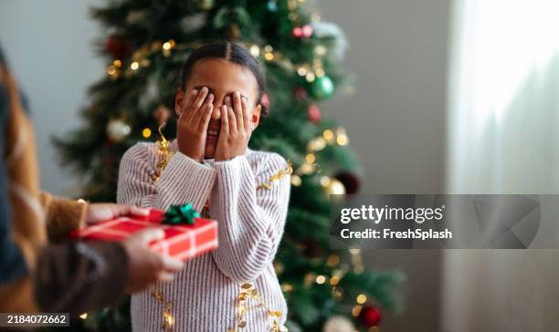 surprised child receives christmas gift with joyful anticipation - holiday spirit stock pictures, royalty-free photos & images