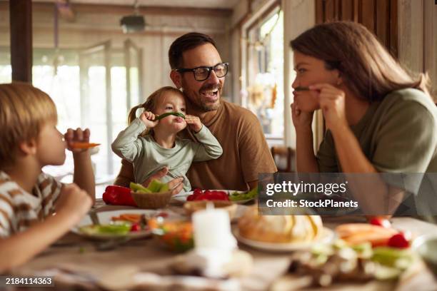 playful family having fun during a meal at dining table. - dining table stock pictures, royalty-free photos & images