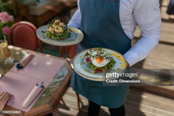 close up of a waiter holding plates with breakfast food on them - ober stockfoto's en -beelden