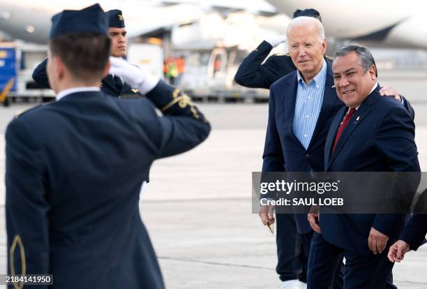 President Joe Biden walks with Gustavo Adrianzen Prime Minister of Peru through an honor cordon as he disembarks from Air Force One upon arrival at...