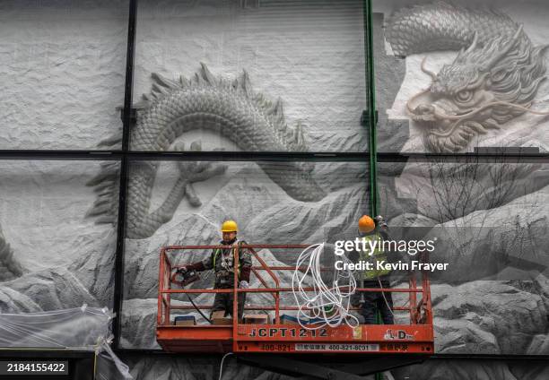 Workers install a large dragon on the side of a clothing store that will soon open at a shopping mall on November 11, 2024 in Beijing, China. In its...