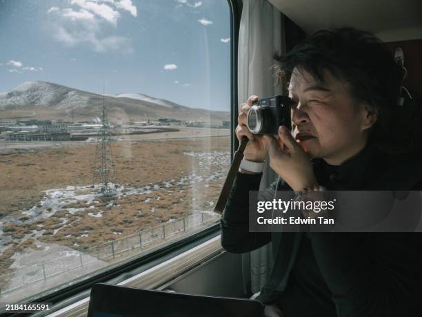 asian chinese female tourist photographing scenery looking through train window in tibet - window frame stock pictures, royalty-free photos & images