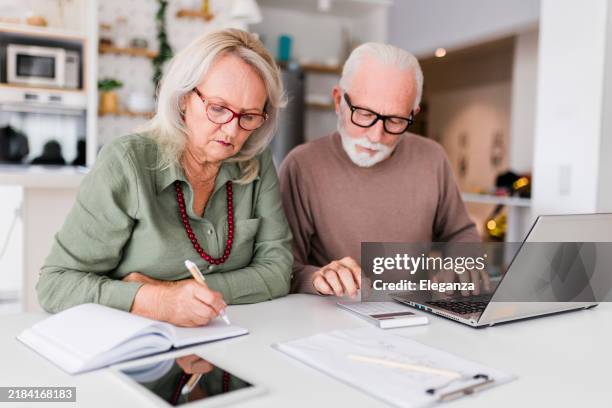 senior couple using laptop while planning their home budget, - pensão documento bancário imagens e fotografias de stock
