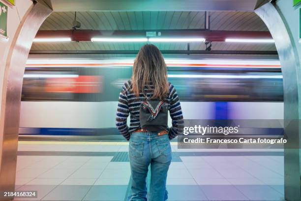 rear view of female passenger with rucksack standing on madrid underground station - subway stock pictures, royalty-free photos & images