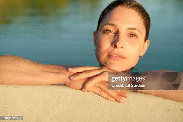 serene woman with wet skin resting at the edge of a pool during sunset - swimmer stock pictures, royalty-free photos & images