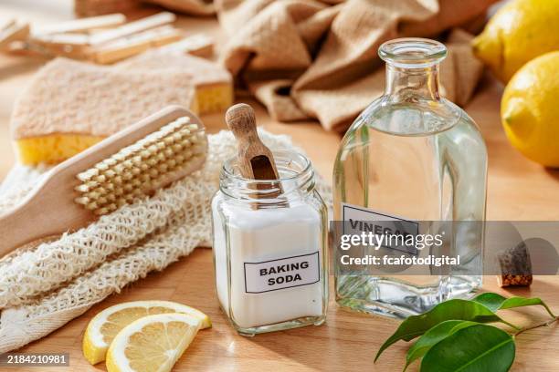 home cleaning with natural and eco friendly products: baking soda, white vinegar, lemon, scrubbing brush and cleaning sponge - vinegar stock pictures, royalty-free photos & images
