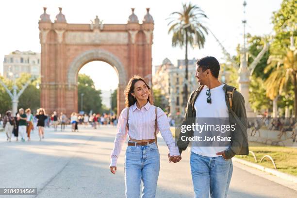 tourists holding hands and walking near arc de triomf in barcelona - urban exploration stock pictures, royalty-free photos & images