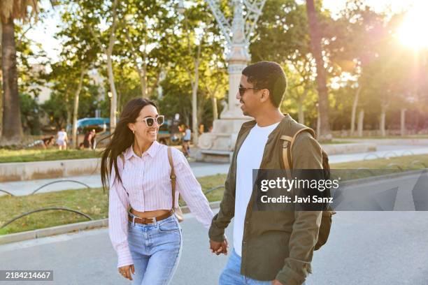 happy tourists couple walking and holding hands in barcelona city park - urban exploration stock pictures, royalty-free photos & images