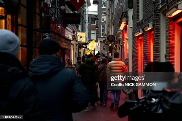 Pedestrians walk through the Red Light District in Amsterdam, on November 15, 2024. By a canal in Amsterdam's red light district, one of the...
