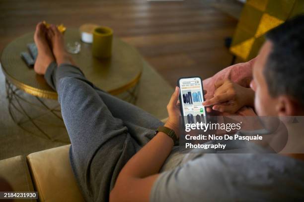 man purchasing clothes on a mobile app - accro du shopping photos et images de collection