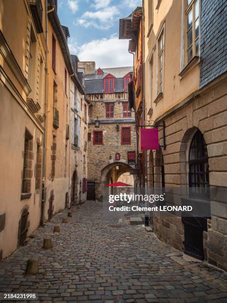 view of a cobblestone narrow street in the historic district of rennes with the back facade of the medieval entrance gate of the city at the end of it, the portes mordelaises (also called porte mordelaise), ille-et-vilaine - bretagne (brittany) - france. - rennes france stock pictures, royalty-free photos & images