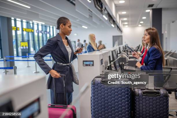 woman engaging with airline staff at check-in counter - security check stock pictures, royalty-free photos & images